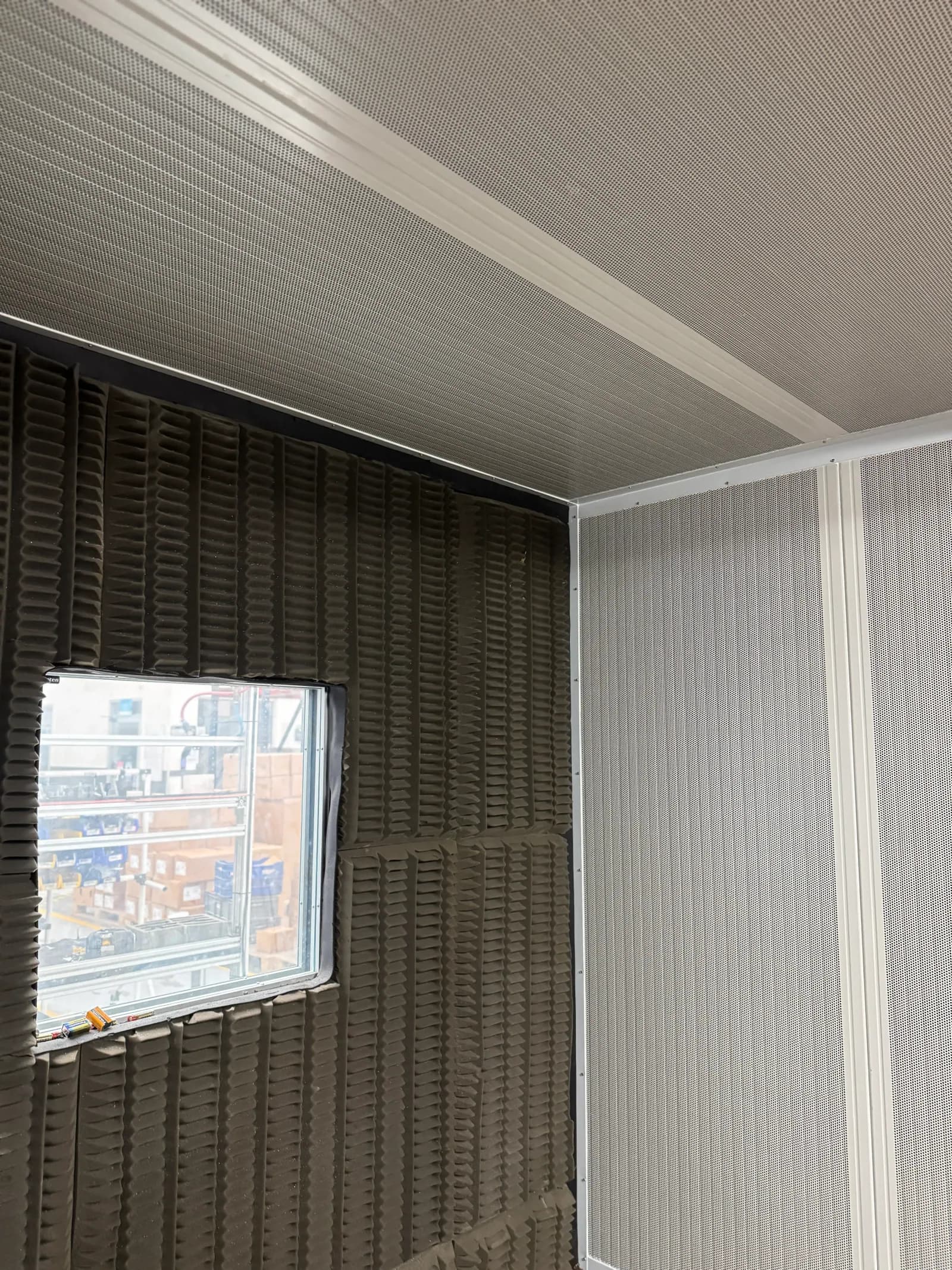 Ventana acústica y panel microperforado en la esquina de un cuarto acústico